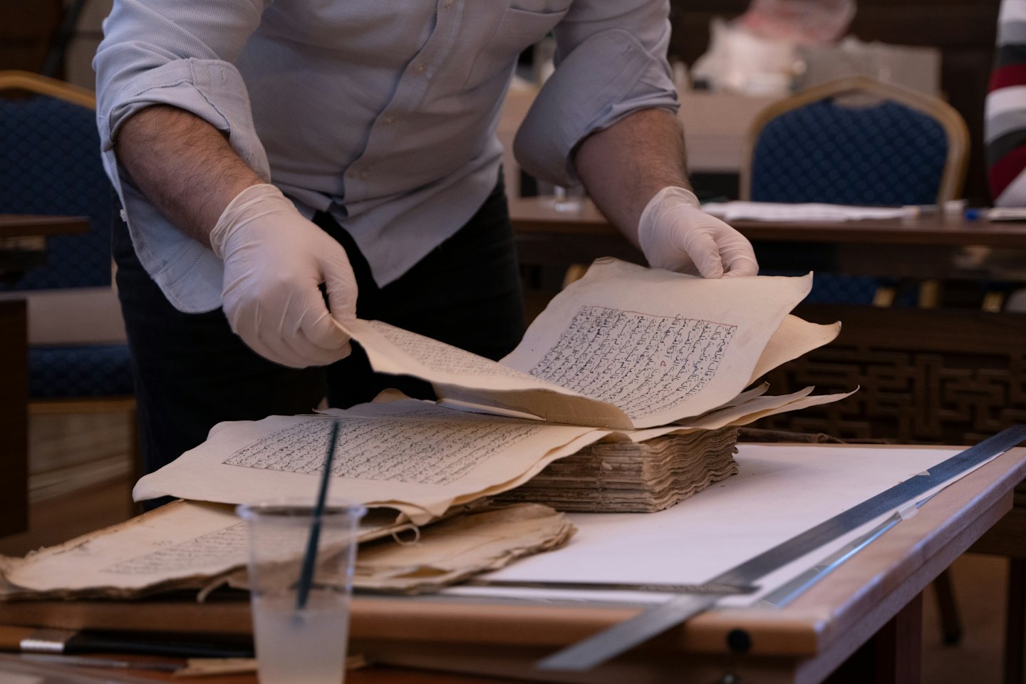 Archivista con guanti esamina vecchi documenti scritti a mano.