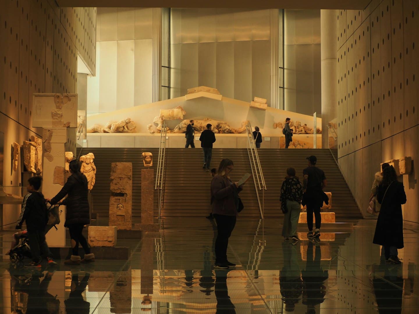 Visitatori ammirano sculture antiche in un museo moderno.